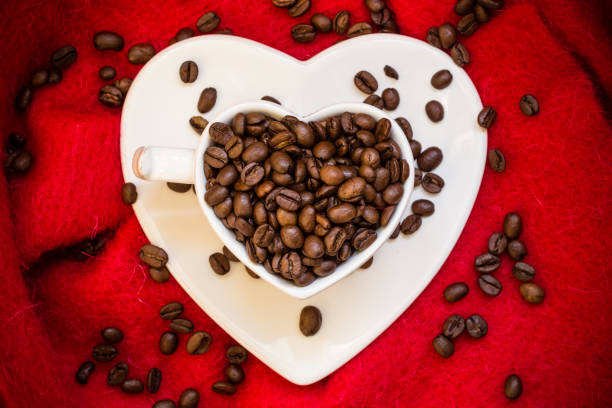 istock Heart shaped cup with coffee beans on red 836817252