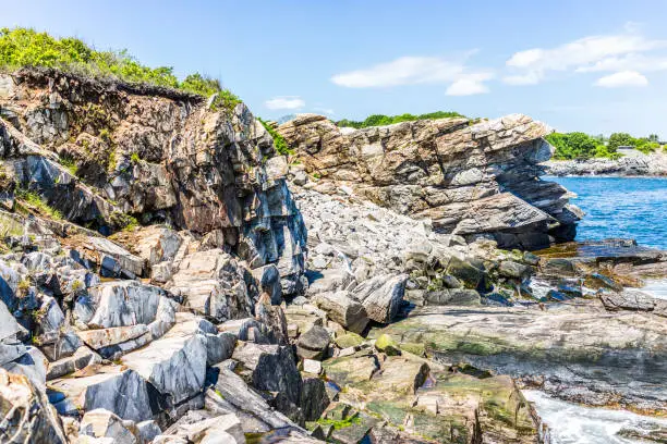 Cliff rocks side view by Portland Head Lighthouse in Fort Williams park in Cape Elizabeth, Maine during summer day