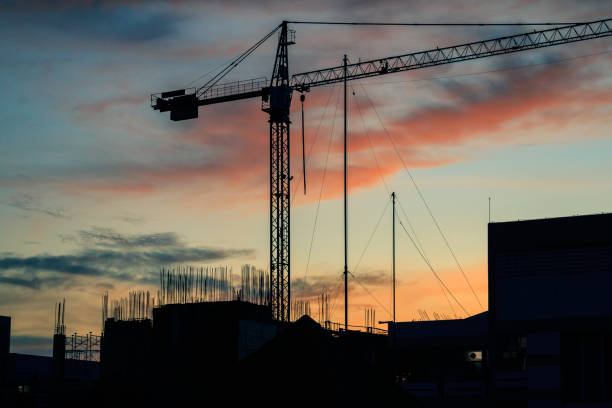 istock cranes under building. colorful sunset sky and big high crains under a new construction site of high-rise building. 837006286