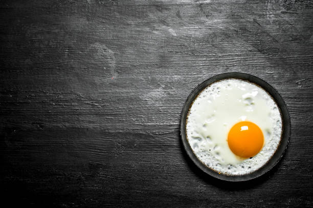istock Fried egg in a frying pan. On black wooden background. 837061452