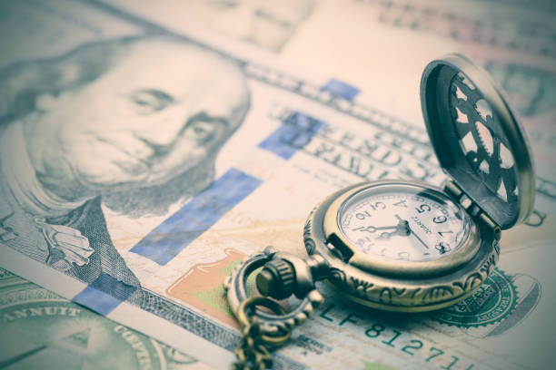 Classic pocket watch on a hundred US dollar bill. Vintage / retro color style : Classic pocket watch on a hundred US dollar bill. A concept / idea of time value of money (TVM), money in hand today is worth more than the same amount in the future. length stock pictures, royalty-free photos & images