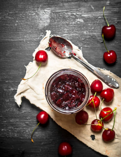 istock Cherry jam in a jar on the old fabric. 837100604