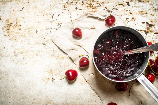 istock Cherry jam in a saucepan on the old fabric. 837105432