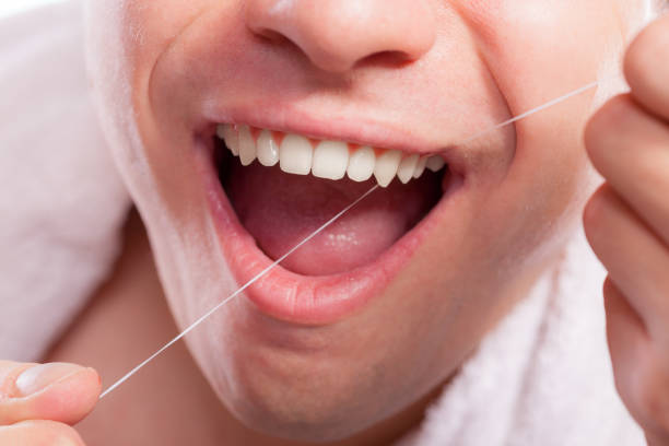 istock Young man cleaning her white teeth with dental floss 837105756