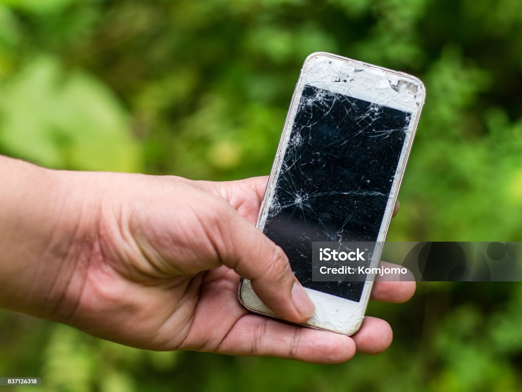 Die Hand des Menschen halten eine defekte Handys mit grüner Natur Hintergrund - Lizenzfrei Abbrechen Stock-Foto