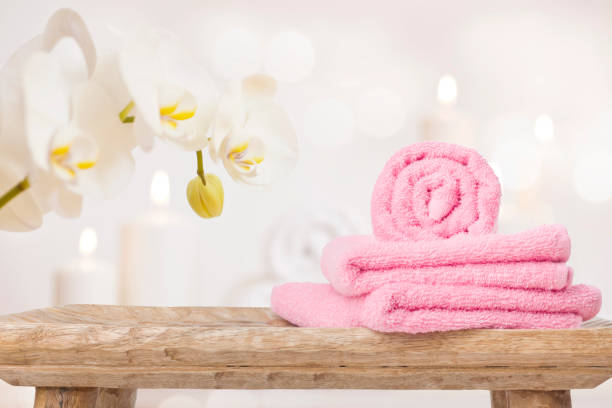 Spa towels on wooden table and orchid over abstract background