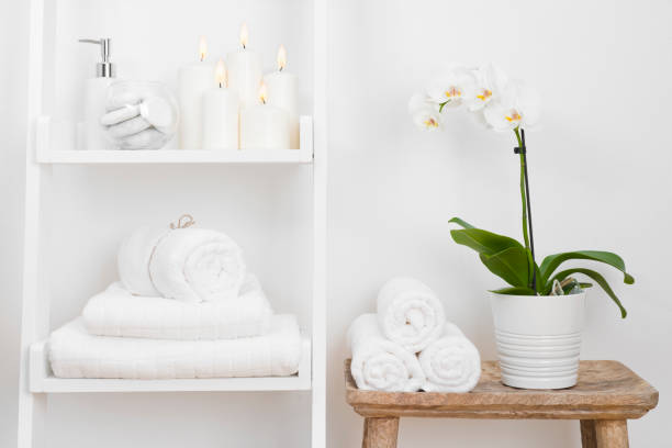 mensola con asciugamani puliti, candele, vaso di fiori sul tavolo in legno del bagno - cotton white textured toiletries foto e immagini stock