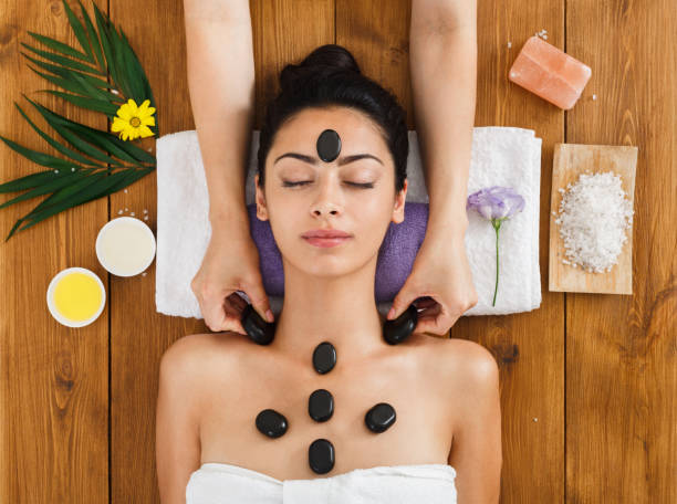 kosmetikerin machen stein massage-spa für frau im wellness-center - massaging spa treatment stone massage therapist stock-fotos und bilder