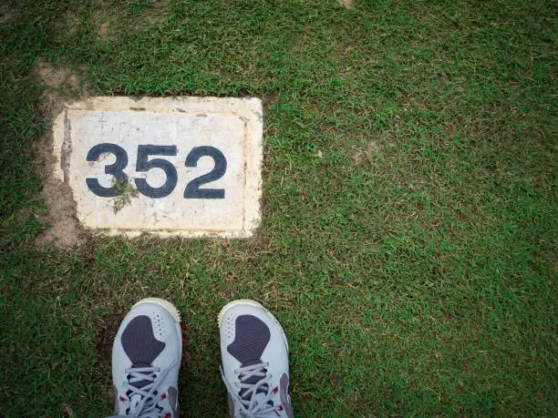 Yard label on the PAR 4 lady tee with lady golf shoes on green grass in a golf course