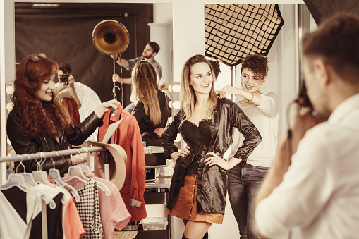Stylist putting stylish clothes on fashion model at backstage