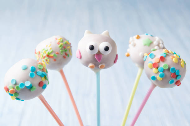 Homemade fresh assorted cake pops with multi colored sprinkles and owl shape on a blue background, sweet food for kids