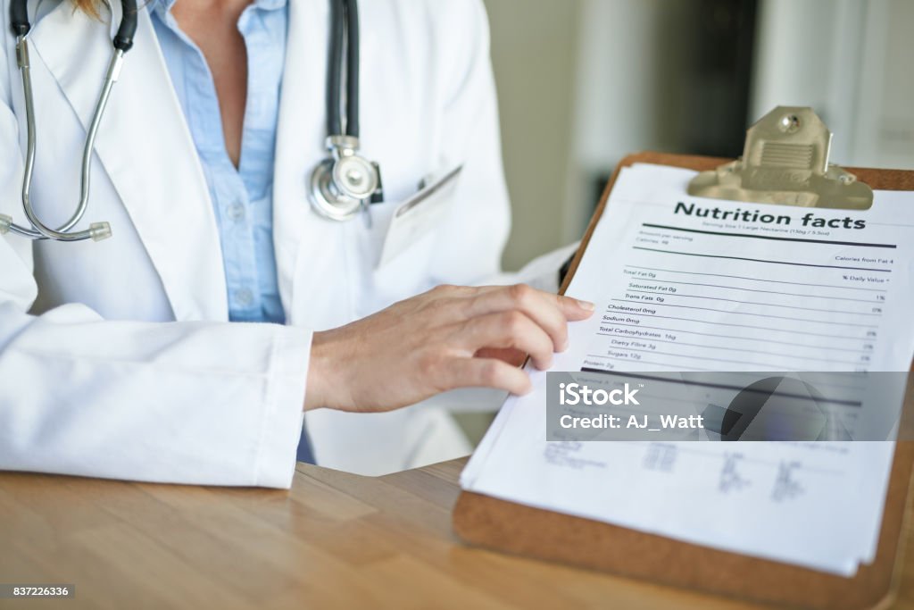 So you can make an informed decision Cropped shot of a doctor holding a clipboard with a nutritional facts table on it in a consulting room Nutritionist Stock Photo