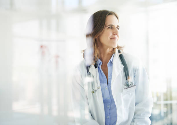 With her, good health is in sight Shot of a mature doctor looking thoughtful in a consulting room lab coat photos stock pictures, royalty-free photos & images