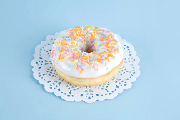 a multicolor donuts presented on a doily paper and a pop colorful background.