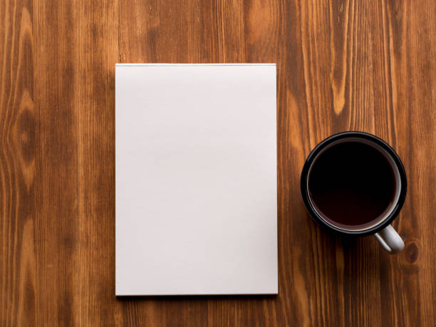 istock tea Cup and open Notepad with a clean white page on wooden table, top view 837277566