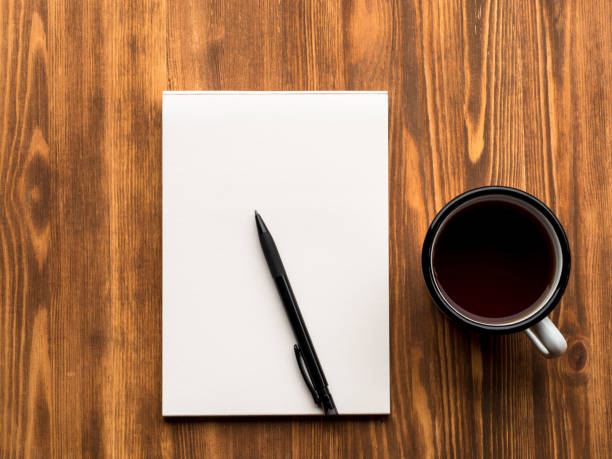istock tea Cup, pencil or pen and open Notepad with a clean white page on wooden table, top view 837277692