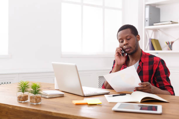 istock Young black businessman read documents and talk on mobile in modern white office 837299974