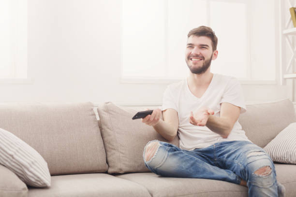 istock Amused young man wathing tv at home 837317192