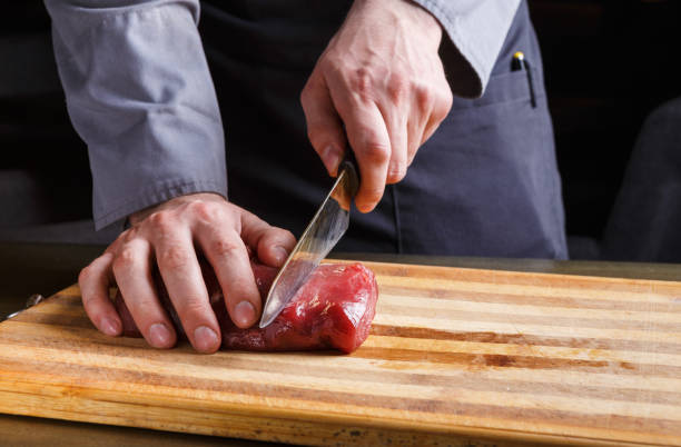 istock Chef cutting filet mignon on wooden board at restaurant kitchen 837320576