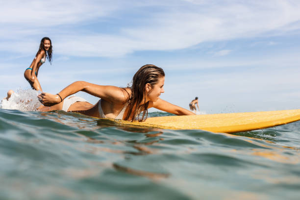 2 美しいスポーティな女の子は海でサーフィンします。 - women sensuality surfing water sport ストックフォトと画像