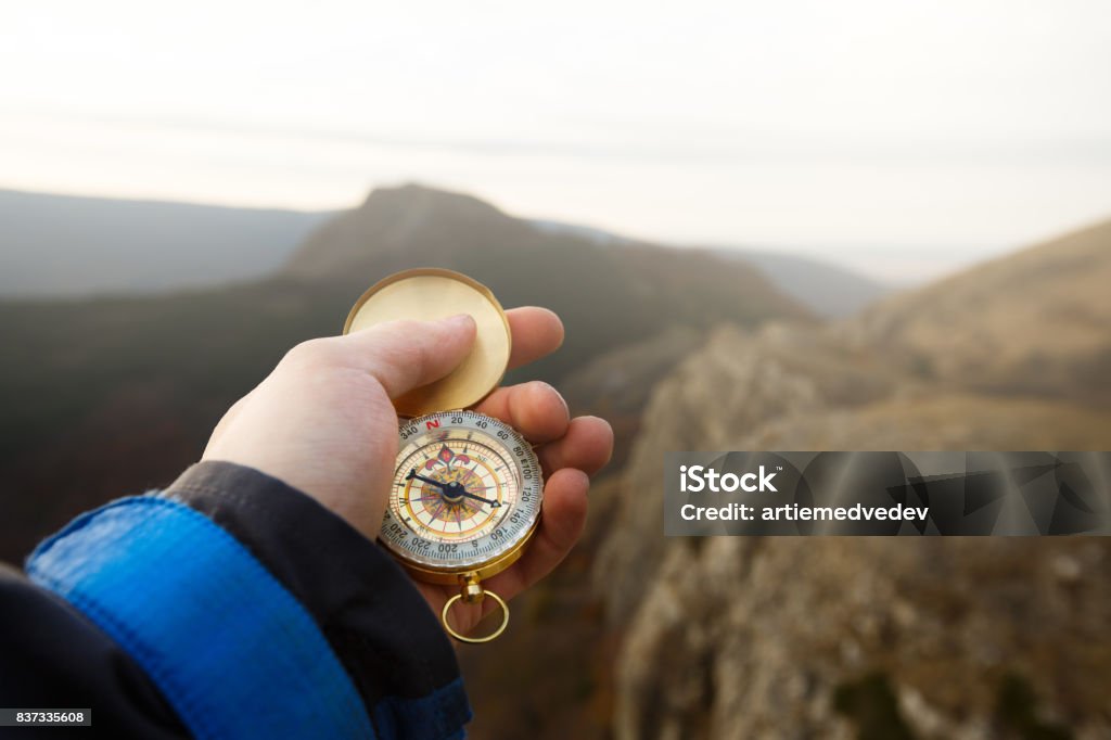 Foto do ponto de vista do homem explorador busca direção com bússola de ouro em sua mão com fundo de montanhas outono - Foto de stock de Montanha royalty-free