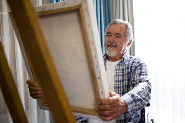 istock Senior man looking at painting while sitting on wheelchair 837338680