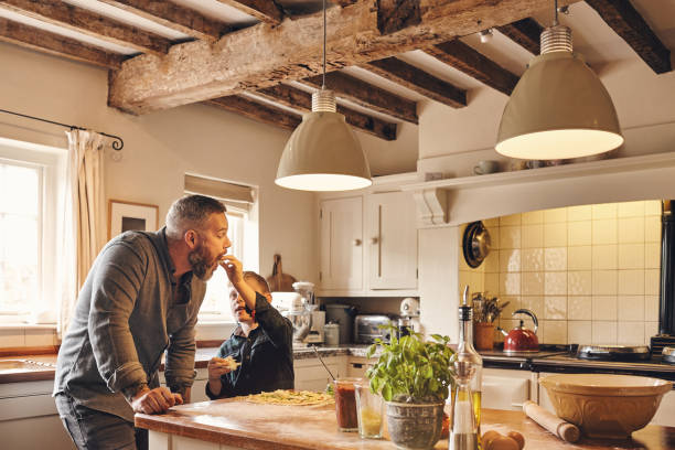 Father and son eating pizza in kitchen at home