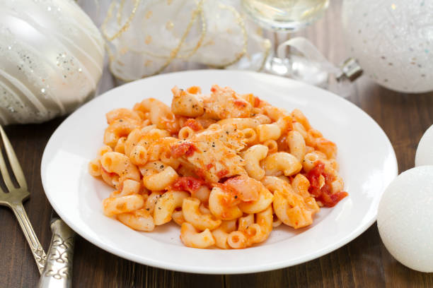 pasta with fish and tomato sauce on white plate on brown wooden background