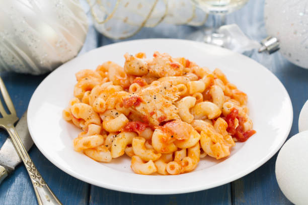 pasta with fish and tomato sauce on white plate on wooden background