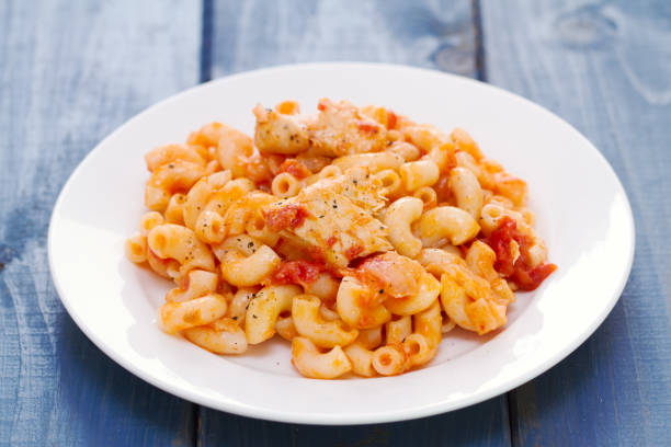 pasta with fish and tomato sauce on white plate on blue wooden background