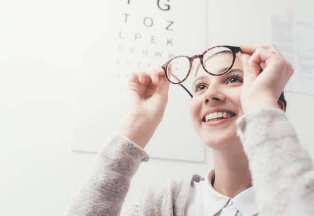 glückliche frau, die versucht ihre neue brille - optometrie stock-fotos und bilder