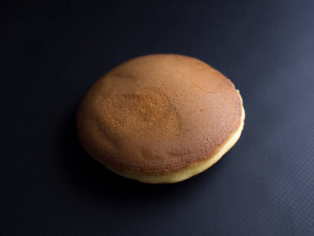 Dorayaki isolated on black background Dorayaki - Japanese cake made from two small "pancakes", filled with a red bean paste. Isolated on black background. red bean dessert stock pictures, royalty-free photos & images