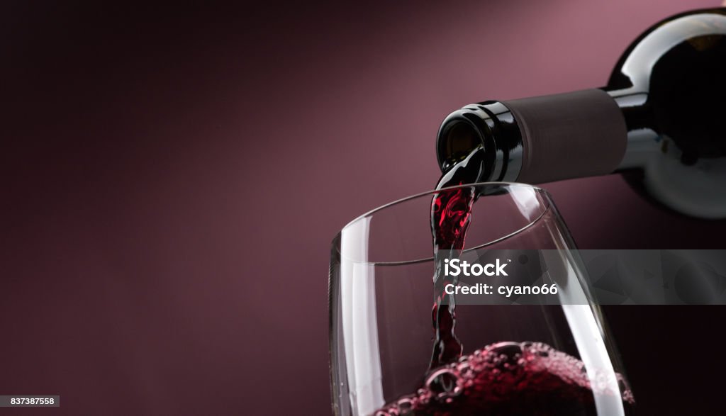 Pouring red wine into a wineglass Pouring red wine from a bottle into a wineglass: wine tasting and celebration Wine Stock Photo