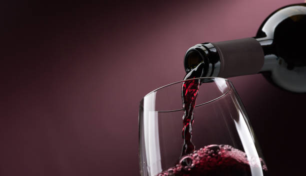 Pouring red wine into a wineglass Pouring red wine from a bottle into a wineglass: wine tasting and celebration wine stock pictures, royalty-free photos & images