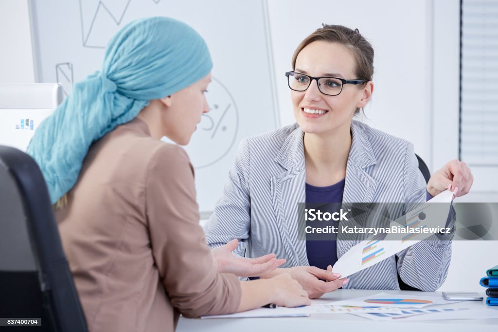 Doctor showing a chart to a patient Smiling doctor showing a chart to her cancer patient Oncology Stock Photo