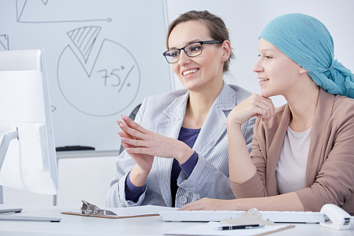 Young doctor talking with her cancer patient in an office