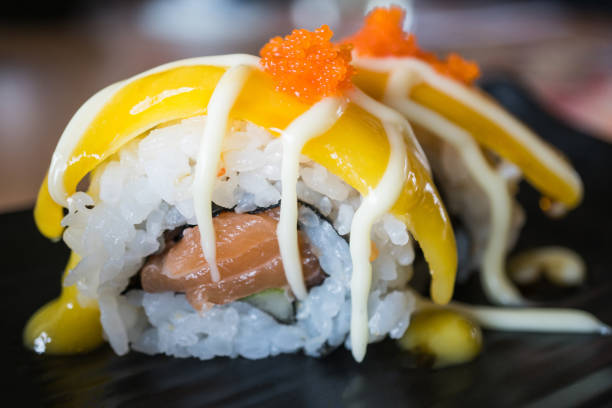 Salmon sushi roll with mango fruit,  japanese food style on black ceramic dish