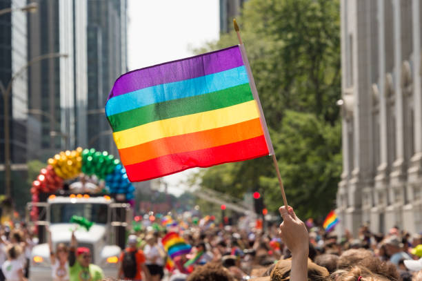 drapeau arc en ciel gay à la marche des fiertés gay montréal avec participants flous en arrière-plan - gay pride rainbow flag homosexual photos et images de collection