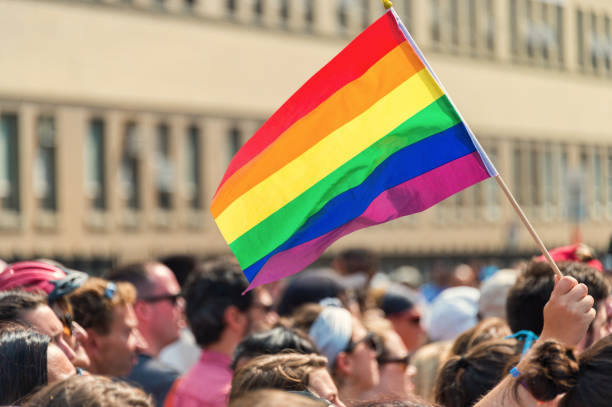 gay regenbogenfahne bei montreal gay-pride-parade mit unscharfen teilnehmern im hintergrund - schwulenehe stock-fotos und bilder