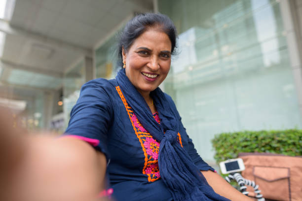 portrait of mature beautiful indian woman relaxing outside siam square mall in bangkok thailand - siam square imagens e fotografias de stock