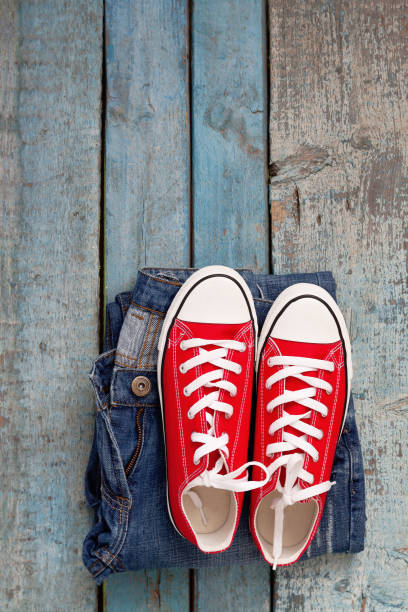 istock Red retro sneakers and jeans on a blue wooden background 837431792