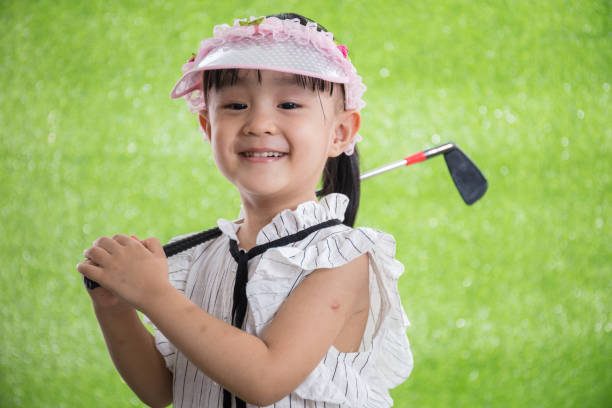 Asian Chinese little girl playing golf on green grass