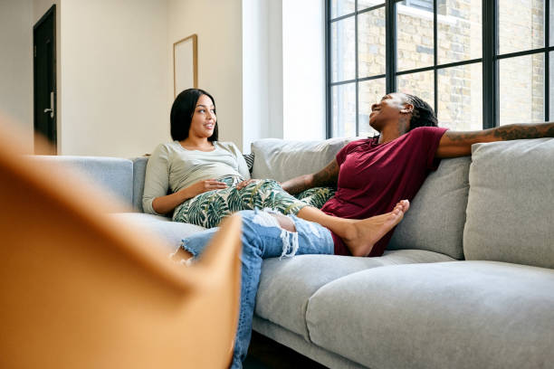 istock Lesbian couple sitting together on sofa 837446498