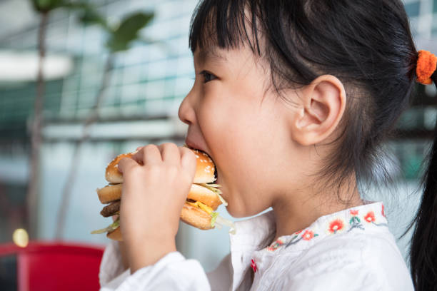 asiatiska kinesiska lilla flicka äter hamburgare - cafe buns eating bildbanksfoton och bilder