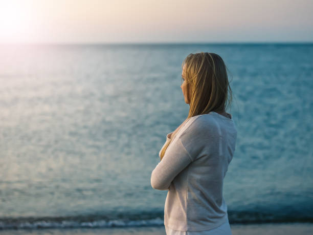 istock Woman with folded on his breast, the hands looks at the setting sun. 837473816