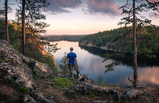 Hiker standing top of the hill front of beautiful idyllic landscape in Mäntyharju, Finland
