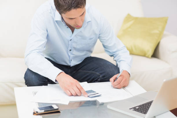 istock Young man with bills calculator and laptop at home 837505326