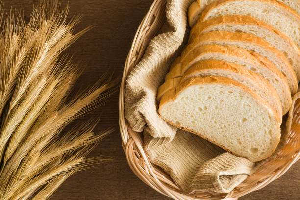 Fresh sliced white bread in the basket on the wooden table in the kitchen. Rustic atmosphere. Healthy eating and lifestyle. Food background.