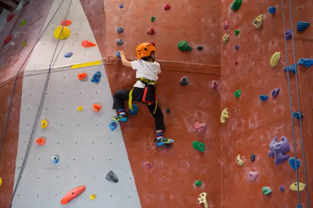 Determined boy practicing rock climbing in fitness studio