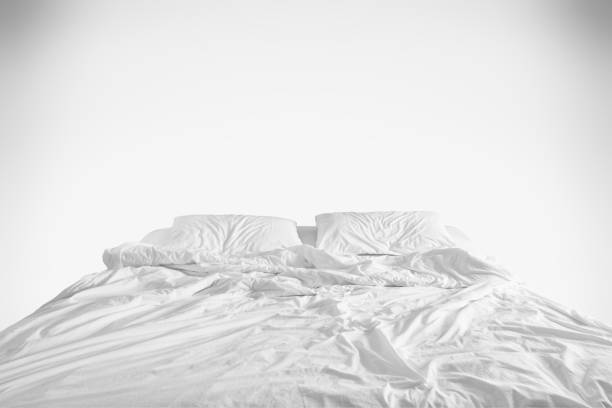 cama desfeita com amassado do lençol, um cobertor e travesseiros após dormir de edredon conforto acordando de manhã no fundo branco - crumpled sheet - fotografias e filmes do acervo